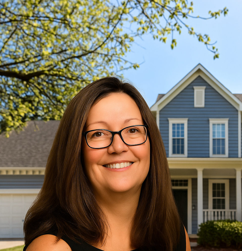 Smiling woman with glasses in front of a suburban house on a sunny day.