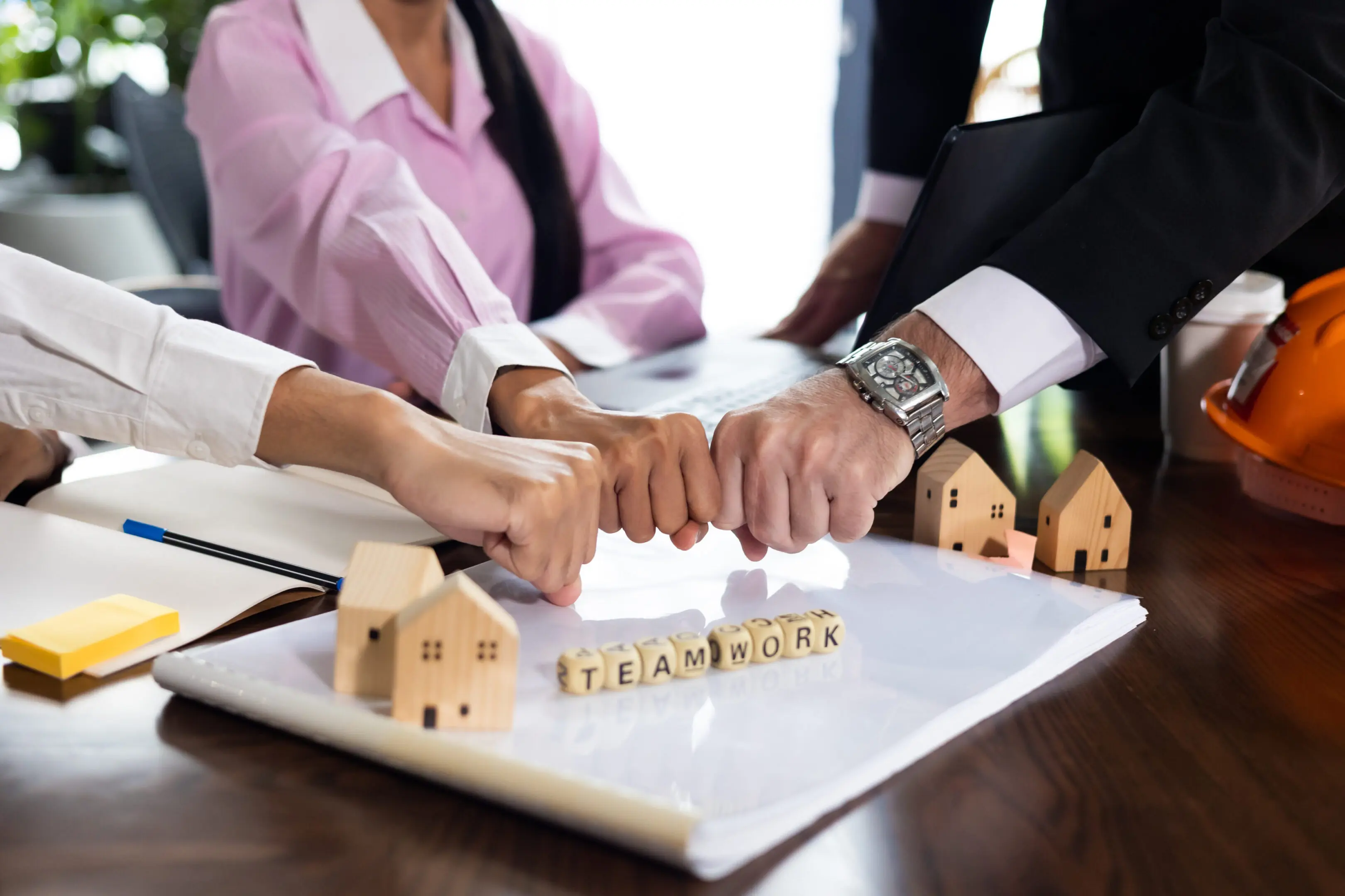 Businesspeople shaking hands over a real estate deal with miniature houses on the table.